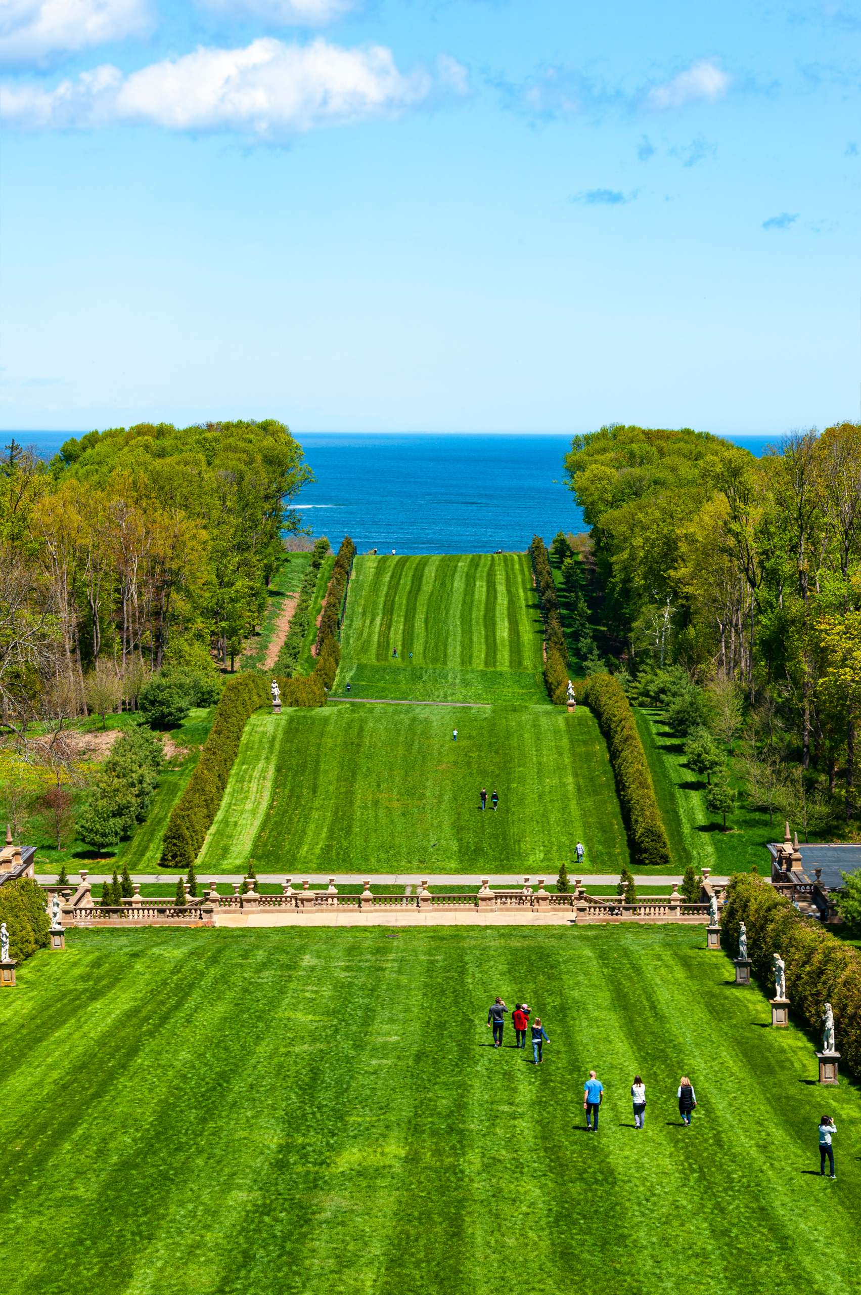 Sweeping green lawns of the Crane Estate at Castle Hill in Ipswich, with visitors strolling toward the Atlantic Ocean in the distance